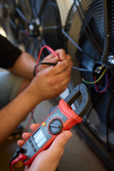 A technician uses a clamp meter to analyze electrical current for safety during repairs