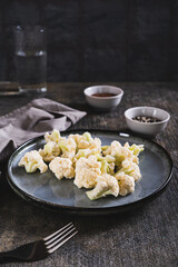 Pieces of raw cauliflower for diet on a plate on the table vertical view