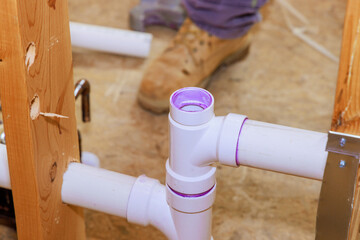 Technician plumber using glue is applied to plastic PVC pipes
