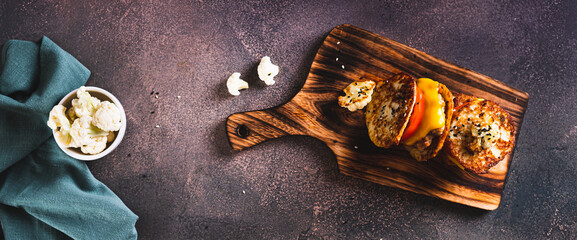 Homemade keto burgers on cauliflower fritters on a board top view web banner