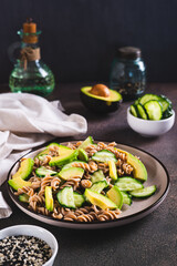 Delicious salad of buckwheat pasta, cucumber and avocado on a plate vertical view