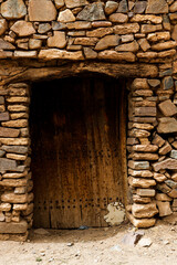 door of an old castle and architecture of stones buildings in a village in the south of the Kingdom of Morocco in the Souss-Massa region