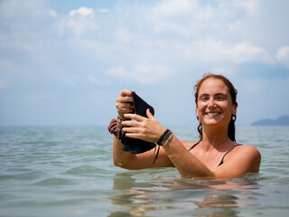 Smiling Woman Holding Snorkel Mask in the Ocean