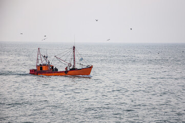 orange fishing boat sailing in the sea	