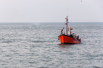 orange fishing boat sailing in the sea