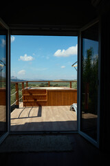 Open door to outdoor deck with hot tub and scenic view