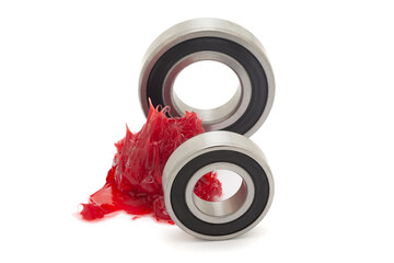 Two tapered roller bearings with red lithium grease (Machinery Lubrication). Isolated on a white background. Front view.