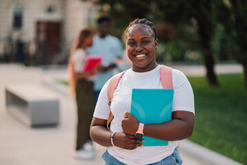 Close up of happy diverse female student with notebook at campus.