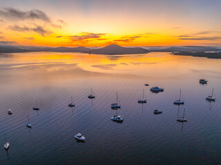 Sunrise over the calm water with boats and reflections