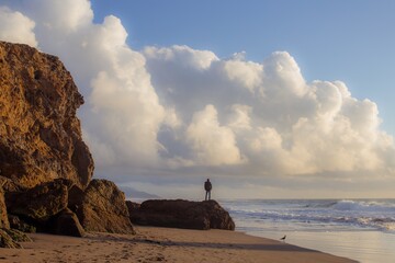 Man standing on a rock looking out over Ocean beach. San Francisco, Califormia, United States of America.