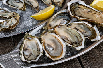 Plate with fresh live oysters with citron, bread, butter and white wine served on ice at restaurant...