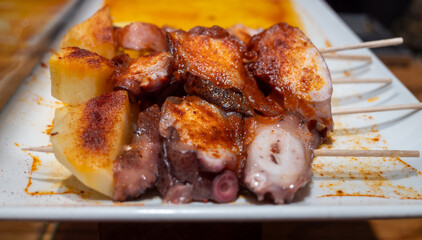 Typical snack of Basque Country, pinchos or pinxtos skewers with small pieces of bread, sea food, eggs, cheese, jamon served in bar in San-Sebastian or Bilbao, Spain, close up