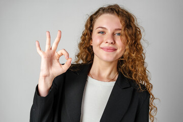 Young Woman Giving Ok Sign on gray background