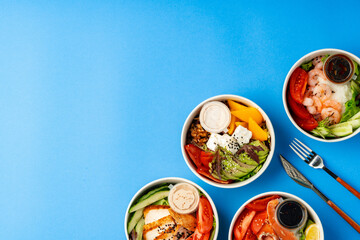 Different poke bowls on blue background top view
