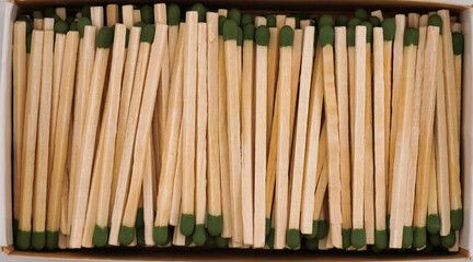 This is a close up picture of matches, sitting within a box, in a neat and organized fashion, showcasing an interesting texture and background.