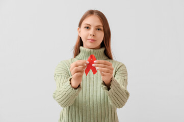 Pretty young woman with red ribbon on white background. World AIDS Day concept