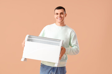 Young man with radiator on beige background