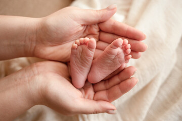 the parent's hand holds the baby's small leg, light close-up photo. family concept