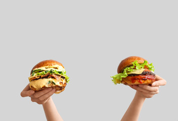 Female hands with tasty burgers on white background