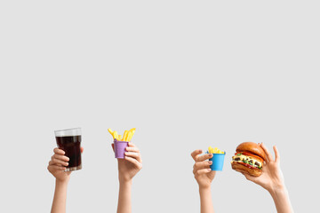 Female hands with tasty burger, french fries and glass of cola on white background