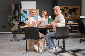 Mature couple with passports sitting in travel agency