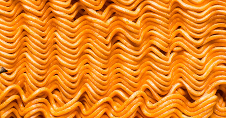 Overhead view of spicy ramen noodles, top view of orange spicy noodles on countertop