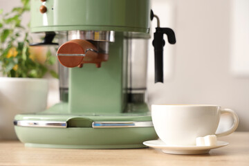 Cup of espresso with sugar near modern coffee machine on wooden table, closeup