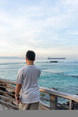 Rear view of a man enjoying the beach atmosphere on the bridge of a sailboat