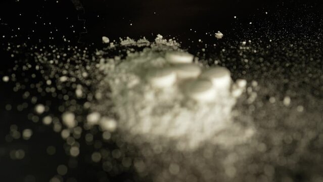 Macro close up at moving crushed drug cocaine powder substance. Opioid crises abuse and addiction. Hard addictive illegal drugs.