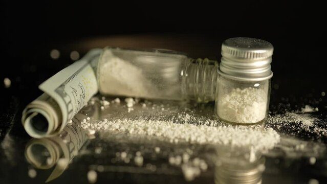 Powdered illegal drugs stored in a glass vial, indicating substance abuse. Ongoing crisis involving opioids and fentanyl. Heroin or crushed oxycodone placed in a container.