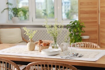 Clean dishes, flowers and fresh pastries on table in stylish dining room
