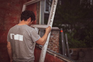 Caucasian male builder inspects dirty window frames.