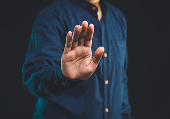 Person shows a stop gesture while standing on a black background.