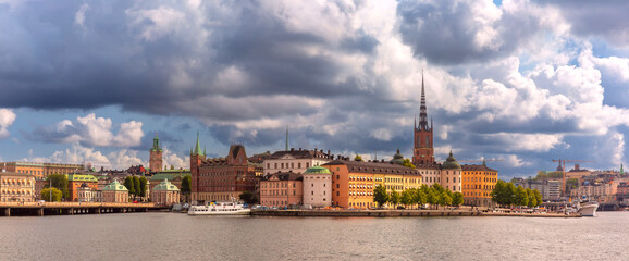 Naklejka premium Panoramic view of historic buildings along the Stockholm waterfront, Sweden under a dramatic sky