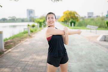 Asian woman stretching her muscles before exercising at the park. Runner stretching her muscles after running. Health and body shape concept.