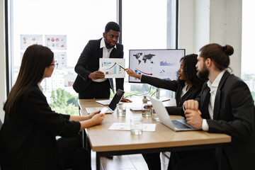 Business team discussing charts and statistics during a meeting in office. Collaborative environment with diverse professionals analyzing data and strategies.