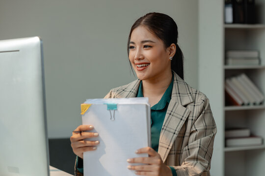 a secretary is organizing stack of paperwork for keep her desk clean, tidy up all finance document on desk because its so messy, a employee archive paper report for neat