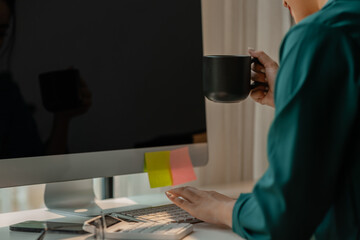 a businesswoman is in the conference meeting, a head of marketing department is listening her team present new marketing strategy plan via computer and holding a cup of coffee