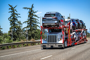 White pro industrial classic car hauler big rig semi truck transporting cars and crossovers on...