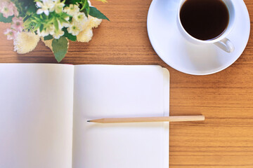 On a brown table With notebook, diary, pencils, white coffee cups And a small bouquet of flowers.