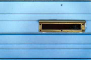 A mail slot in a blue metal door