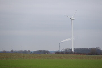 Wind turbine in countryside symbolizes renewable energy smokestack represents traditional industry