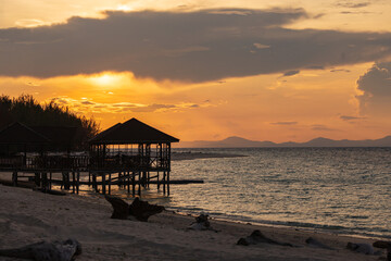 Sunrise silhouettes a dock and gazebo on a beautiful tropical beach