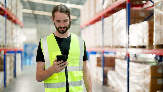Warehouse worker using mobile smartphone and walking in storehouse. Male engineer happy smiling worker celebrating success at warehouse goods storage