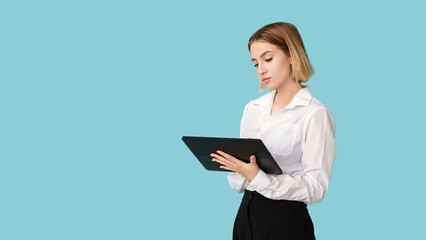 Fototapeta premium Corporate worker. Data analyzing. Online communication. Professional software. Busy elegant woman using tablet isolated on blue empty space.