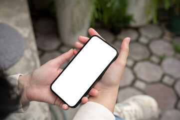 A close-up image of a woman reading or watching videos on her smartphone while sitting outdoors.