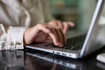 A close-up image of a businesswoman working on her laptop computer, typing on the keyboard.