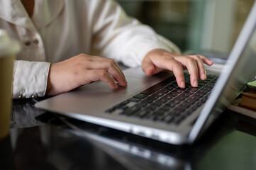 A close-up image of a businesswoman working on her laptop computer, typing on the keyboard.