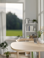 A close-up image of a wooden dining table in a small, minimalist white dining room or apartment.