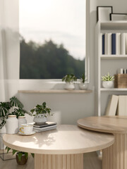 A round wooden table features a coffee cup, books, and decor plants in a minimalist white room.